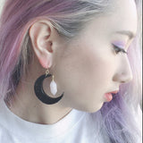 Black moon and star polymer clay earrings with rose quartz crystals shown on model. Perfect for an elegant and witchy look.