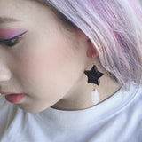 Black moon and star polymer clay earrings with rose quartz crystals shown on model. Perfect for an elegant and witchy look.